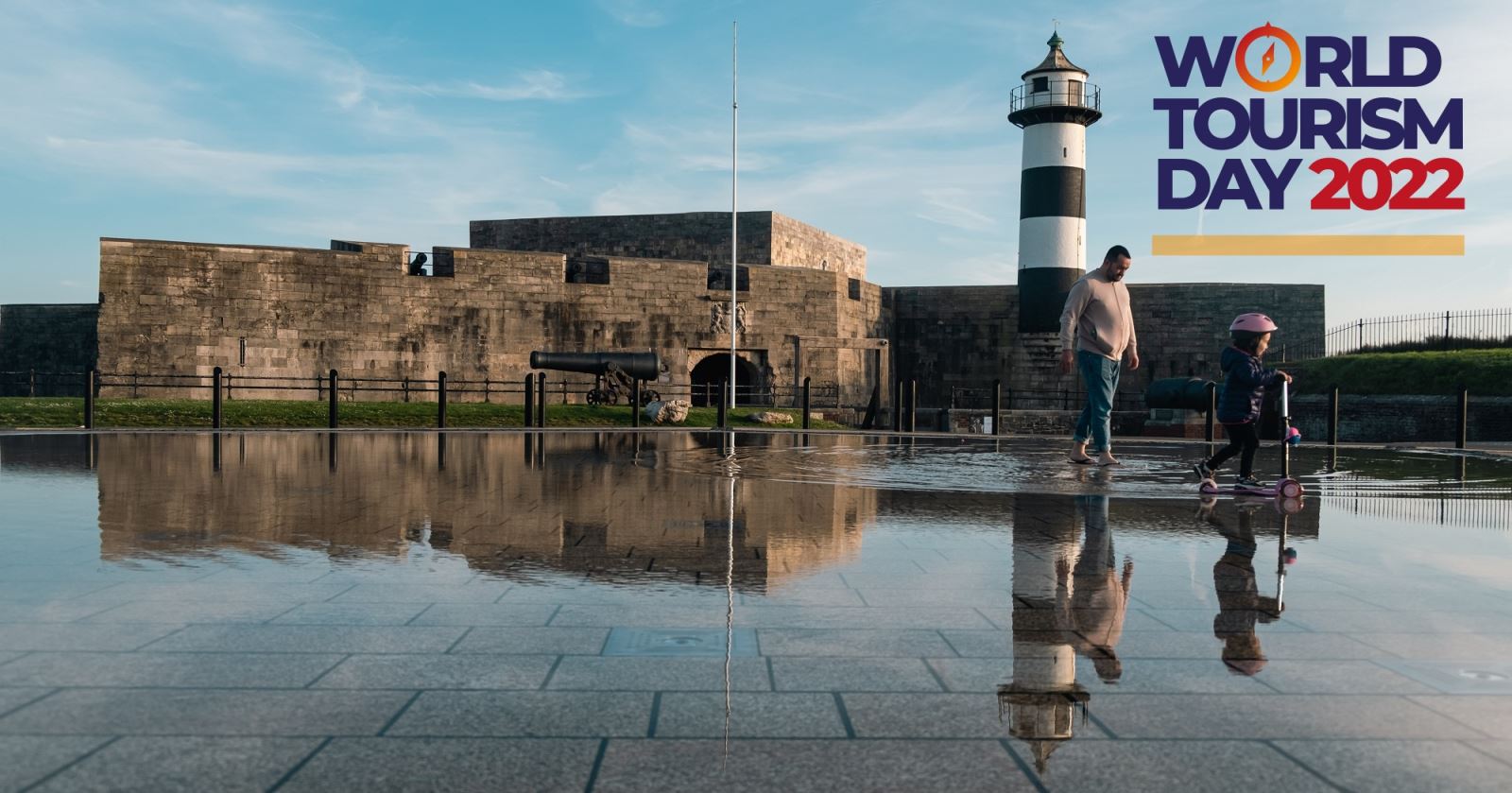 Photograph of an adult and child outside Southsea Castle, overlaid with the World Tourism Day logo
